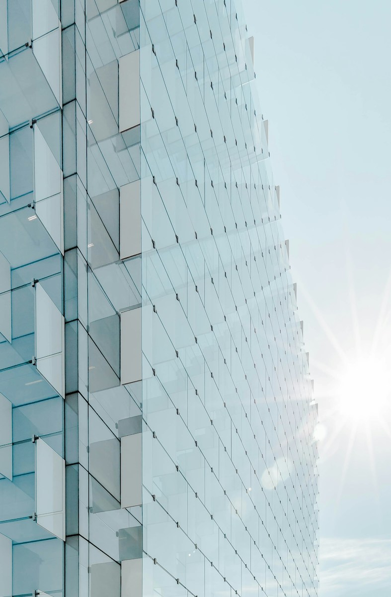 glass panfrel high-rise buildfding unfdder blue sky with sun raise